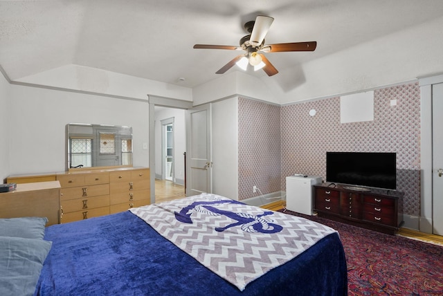 bedroom featuring wallpapered walls, baseboards, vaulted ceiling, and a ceiling fan
