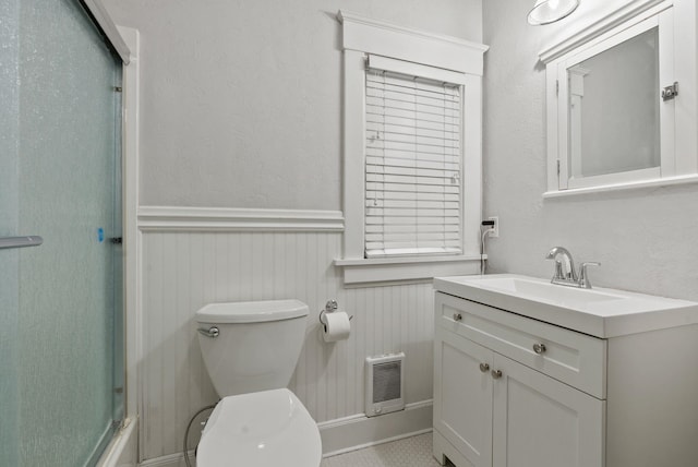 full bath featuring vanity, wainscoting, an enclosed shower, and toilet