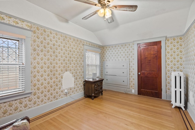 bedroom with radiator heating unit, wallpapered walls, and lofted ceiling