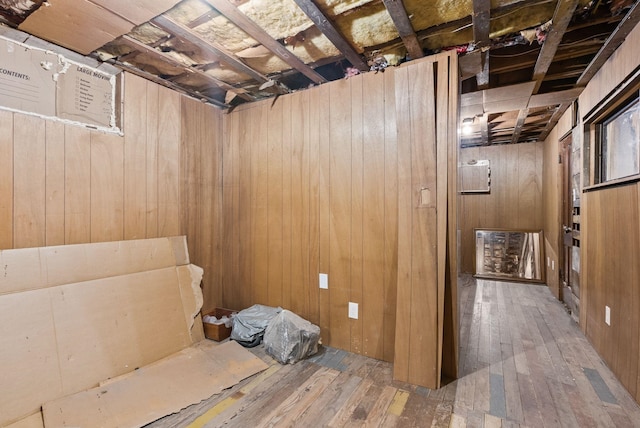 unfinished below grade area featuring hardwood / wood-style floors and wooden walls