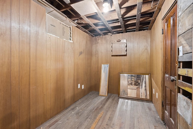 unfinished basement featuring wood walls and hardwood / wood-style flooring