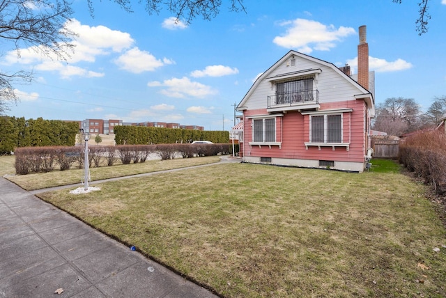 exterior space featuring a balcony, a chimney, a yard, a gambrel roof, and fence