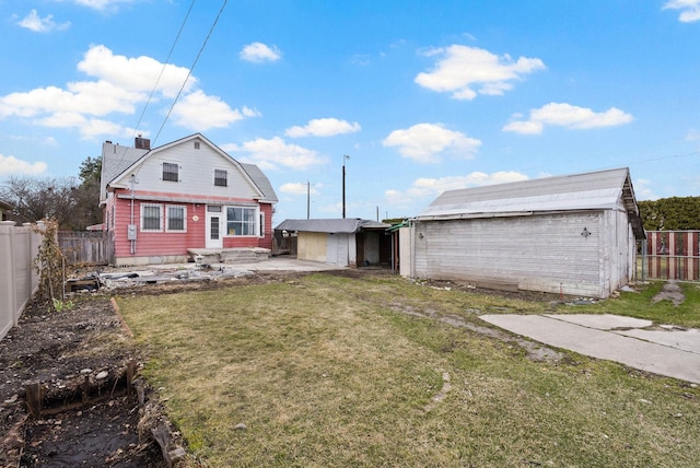 rear view of house with an outdoor structure, a chimney, a shed, a fenced backyard, and a lawn