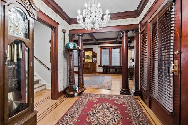hall featuring a chandelier, ornate columns, crown molding, and stairs