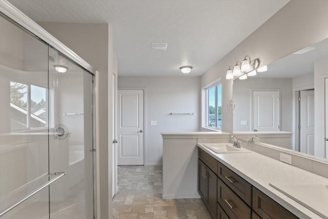 bathroom with a shower with shower door and vanity