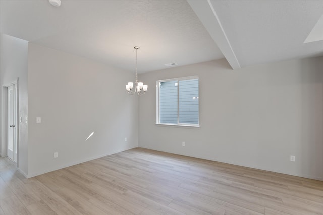 spare room featuring beamed ceiling, a chandelier, and light wood-type flooring