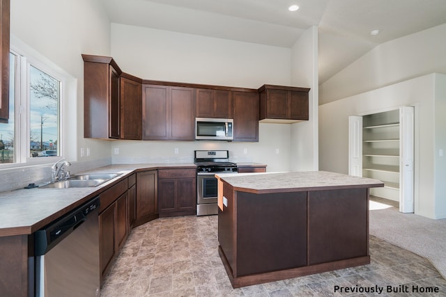 kitchen featuring a center island, lofted ceiling, stainless steel appliances, light carpet, and sink