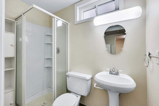 bathroom featuring a shower with shower door and toilet