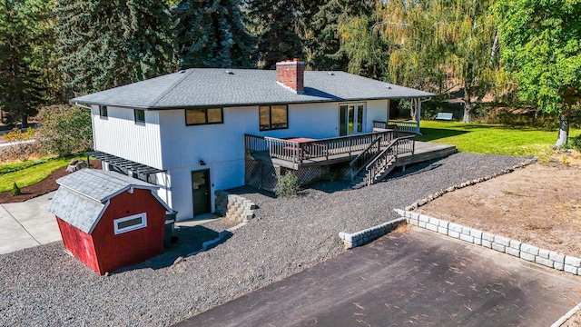 back of property featuring a deck, a yard, and a storage shed