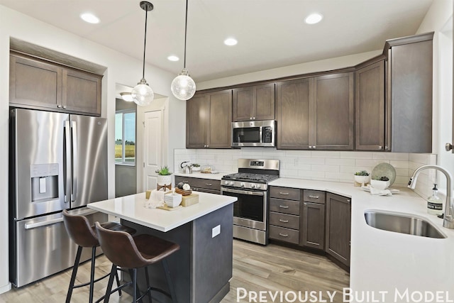 kitchen with tasteful backsplash, a center island, sink, hanging light fixtures, and appliances with stainless steel finishes