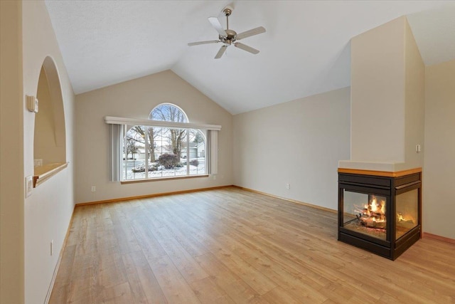 unfurnished living room featuring lofted ceiling, ceiling fan, a multi sided fireplace, and light hardwood / wood-style flooring