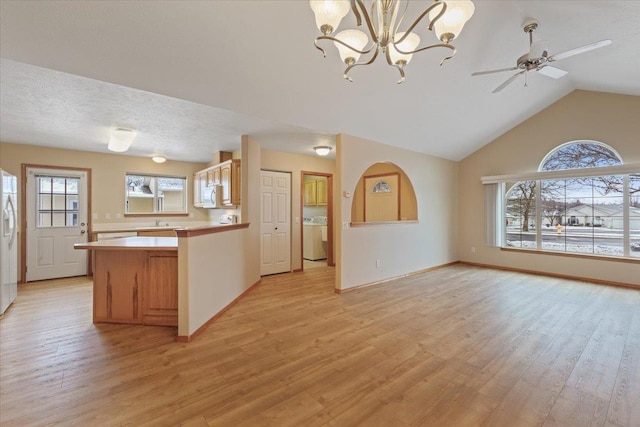 kitchen featuring ceiling fan with notable chandelier, washer / dryer, decorative light fixtures, vaulted ceiling, and light hardwood / wood-style flooring