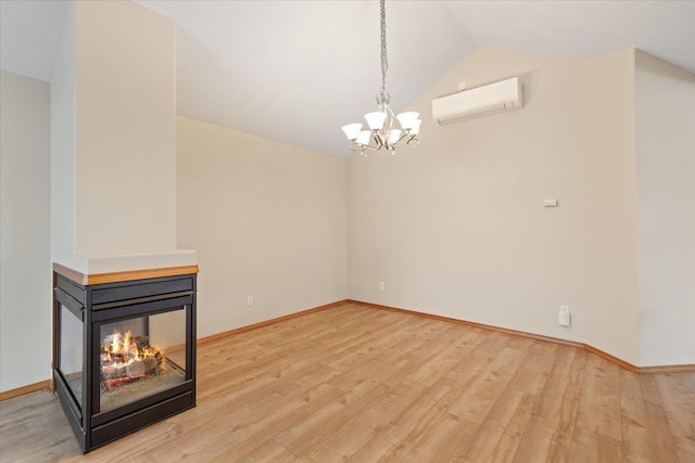 unfurnished living room with lofted ceiling, wood-type flooring, a multi sided fireplace, a wall unit AC, and a notable chandelier