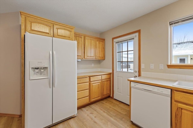 kitchen featuring sink, white appliances, light brown cabinets, and light wood-type flooring