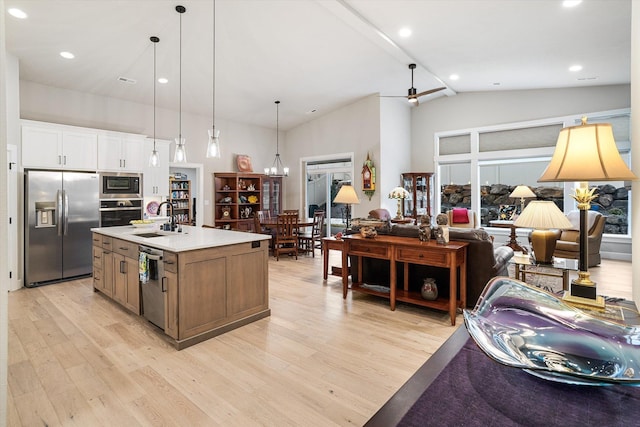 kitchen featuring a center island with sink, stainless steel appliances, vaulted ceiling with beams, white cabinets, and sink