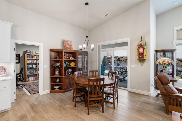 dining space featuring high vaulted ceiling, light hardwood / wood-style flooring, and an inviting chandelier