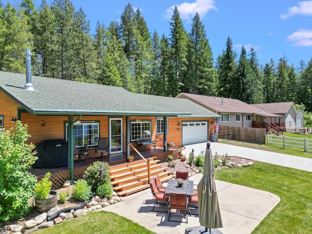 view of front of house featuring covered porch, a garage, and a front lawn