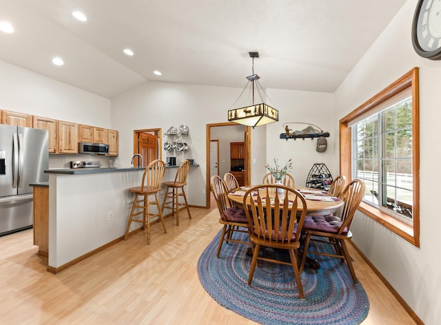 dining room with vaulted ceiling and light wood-type flooring