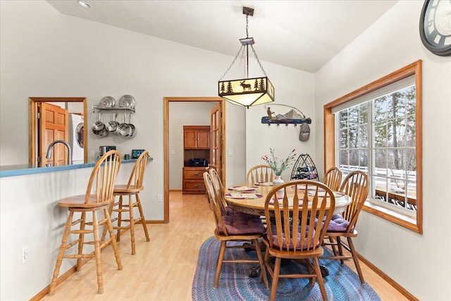 dining area featuring washer / dryer, lofted ceiling, light hardwood / wood-style floors, and sink