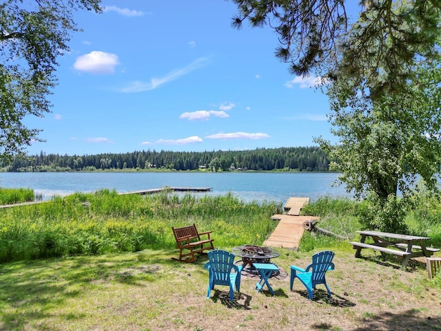 view of yard with a water view, a dock, and a fire pit