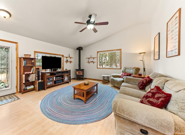 living room featuring ceiling fan, lofted ceiling, a wood stove, and light hardwood / wood-style flooring