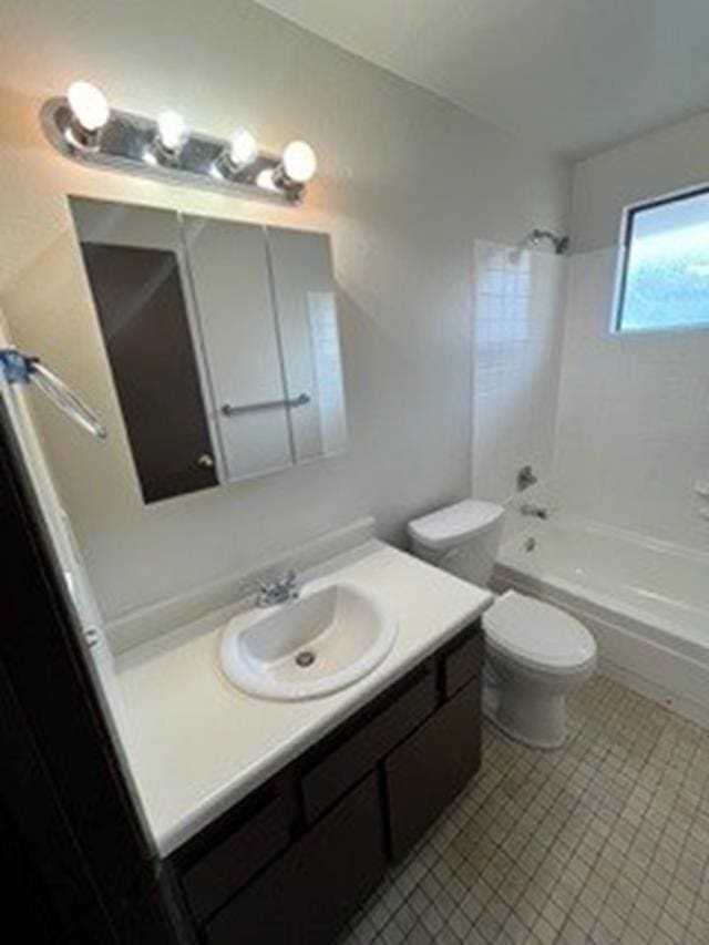 full bathroom featuring toilet, vanity, tiled shower / bath combo, and tile patterned flooring