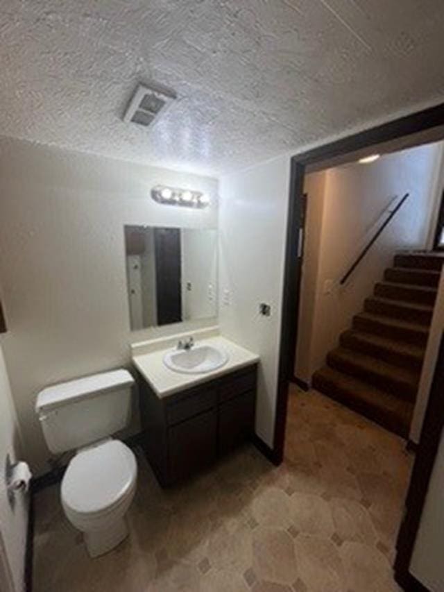 bathroom featuring a textured ceiling, toilet, and vanity