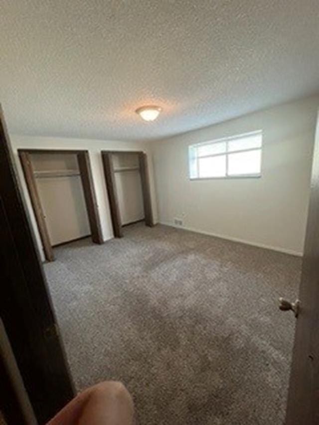 unfurnished bedroom with a textured ceiling and light colored carpet