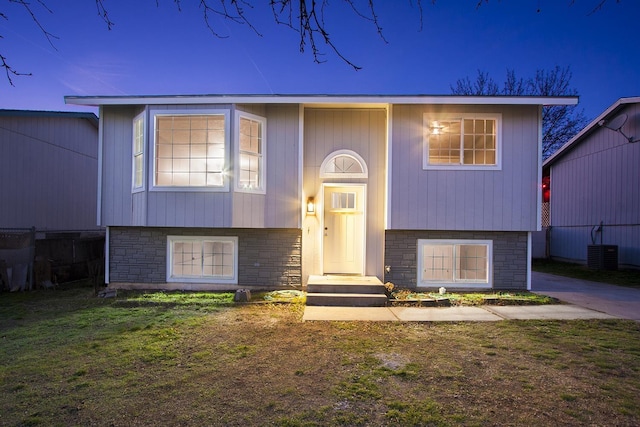 bi-level home featuring a lawn and central air condition unit