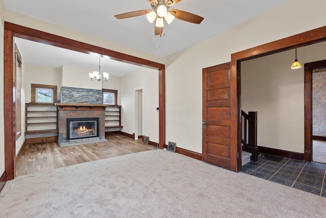 unfurnished living room with dark colored carpet and ceiling fan with notable chandelier