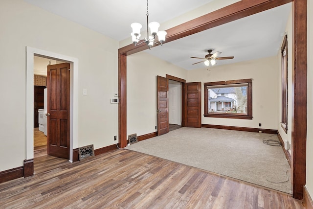 unfurnished room with ceiling fan with notable chandelier and wood-type flooring