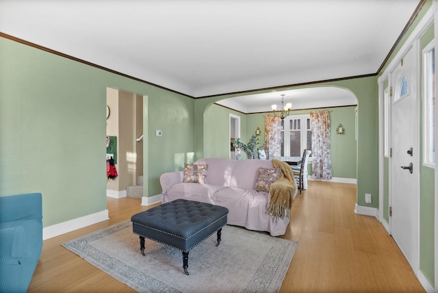 living room with a notable chandelier, ornamental molding, and light hardwood / wood-style flooring