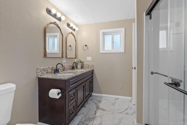 bathroom featuring a shower with door, toilet, and vanity