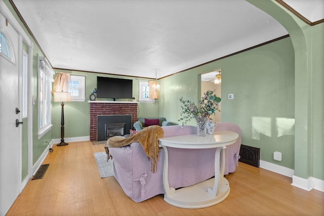 living room featuring ornamental molding, a fireplace, and light hardwood / wood-style flooring