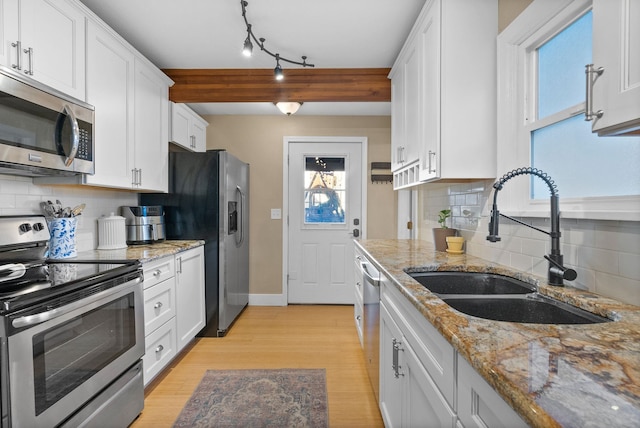 kitchen with tasteful backsplash, sink, white cabinetry, stainless steel appliances, and light stone counters