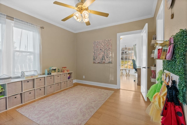 playroom with ceiling fan, crown molding, and light hardwood / wood-style floors