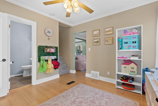 playroom with ceiling fan, wood-type flooring, and ornamental molding