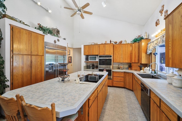 kitchen with ceiling fan, a center island, black appliances, sink, and high vaulted ceiling