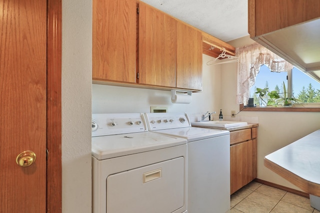 washroom with cabinets, sink, light tile patterned floors, and washing machine and clothes dryer