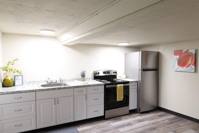 kitchen with sink, white cabinetry, light hardwood / wood-style flooring, appliances with stainless steel finishes, and a textured ceiling