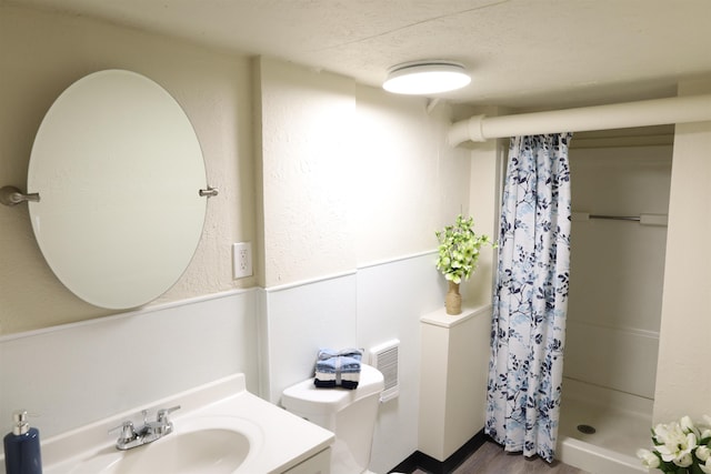 bathroom featuring toilet, vanity, a shower with shower curtain, and a textured ceiling