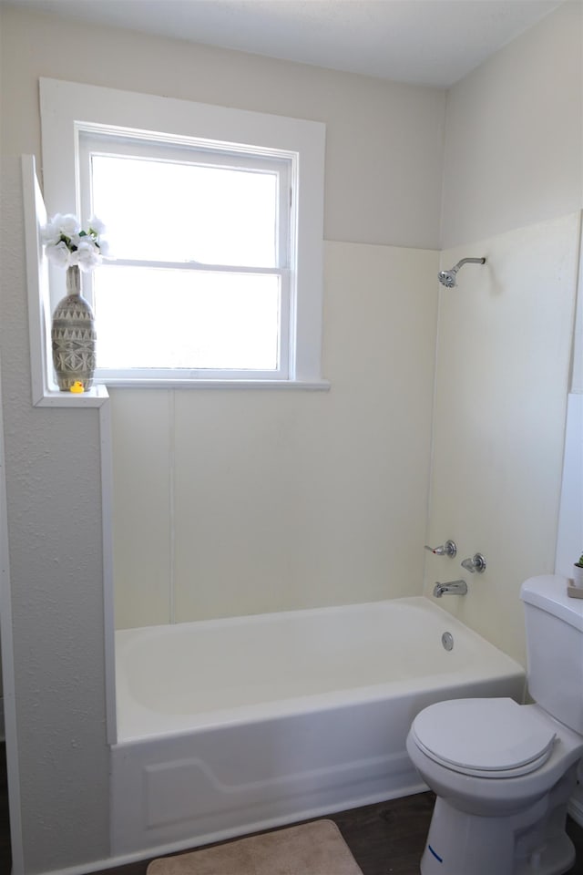 bathroom with toilet, wood-type flooring, and shower / washtub combination