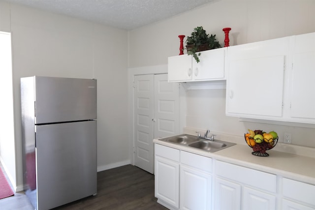 kitchen with dark hardwood / wood-style floors, sink, a textured ceiling, white cabinets, and stainless steel fridge