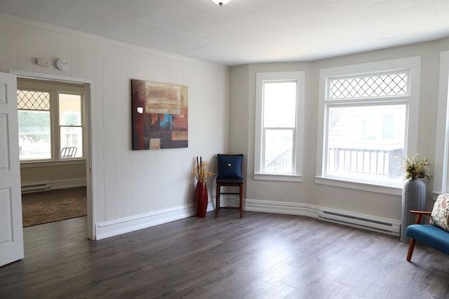 living area with plenty of natural light, a baseboard heating unit, and dark hardwood / wood-style floors