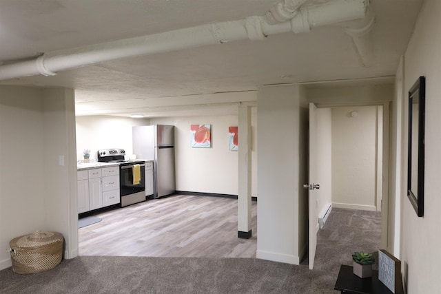 kitchen with white cabinetry, appliances with stainless steel finishes, and light carpet