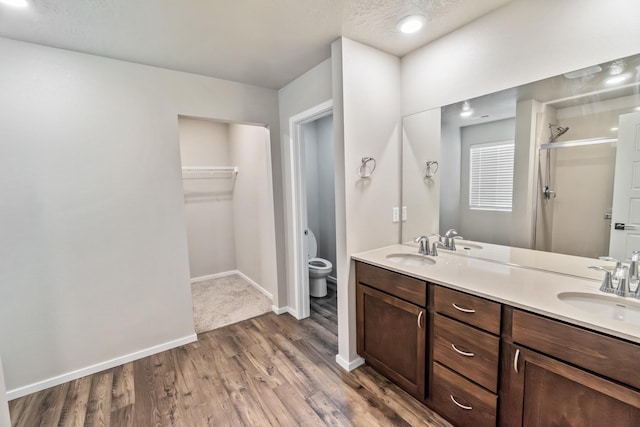 bathroom with hardwood / wood-style floors, a textured ceiling, vanity, toilet, and walk in shower