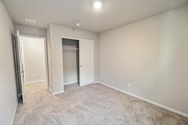 unfurnished bedroom with a closet and light carpet