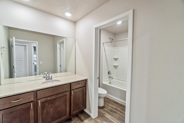 full bathroom featuring toilet, vanity, hardwood / wood-style flooring, shower / bath combination, and a textured ceiling