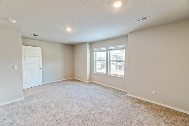 empty room with light colored carpet and a textured ceiling