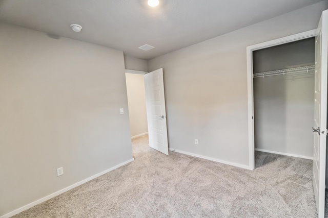 unfurnished bedroom featuring light carpet and a closet